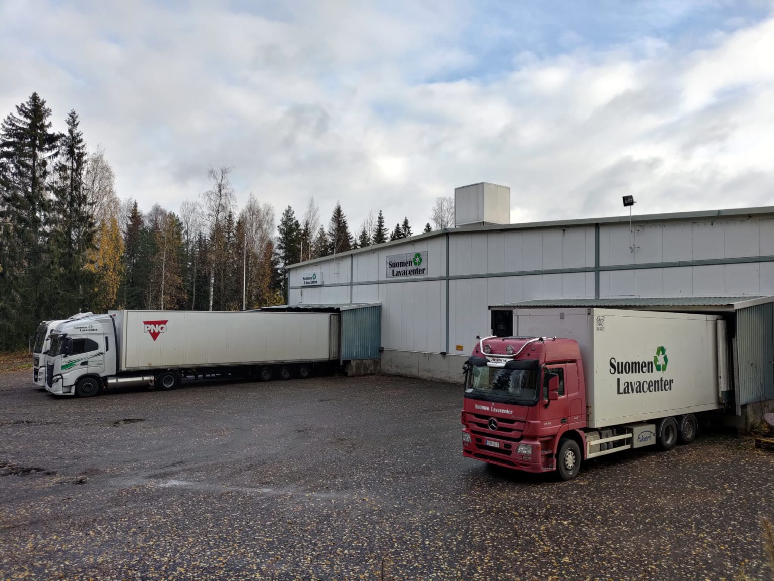 Suomen Lavacenterin punainen kuorma-auto ja rekka varaston lastauslaitureilla Hyvinkäällä