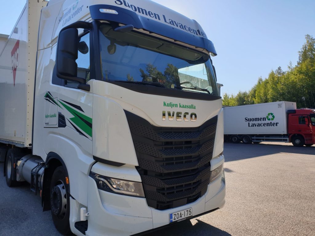 Suomen Lavacenterin valkoinen IVECO-rekka ja punainen kuorma-auto varaston pihassa Hyvinkäällä